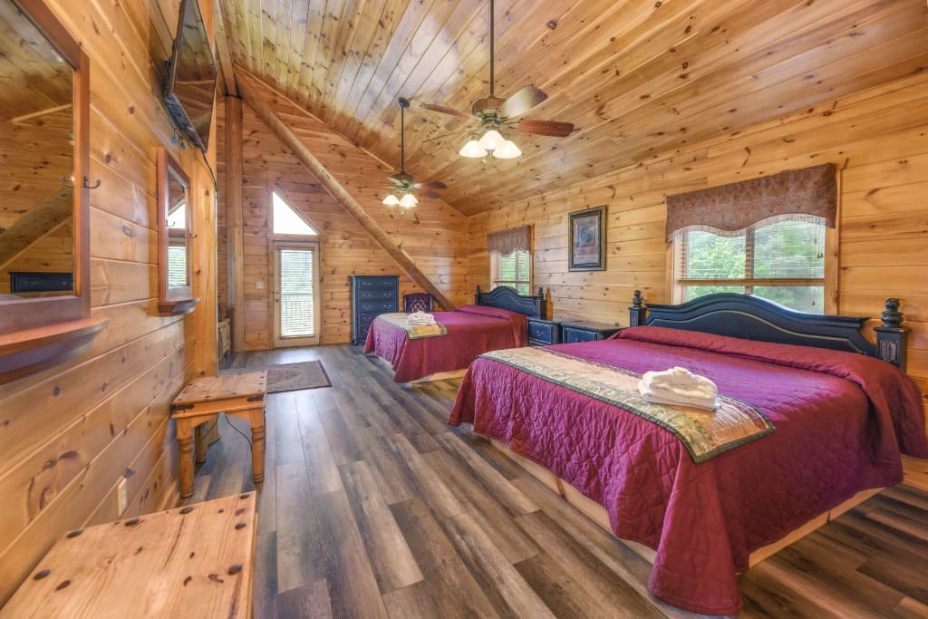 Spacious bedroom with two beds and wood-paneled walls at Moose Hollow Lodge in Sevierville TN.