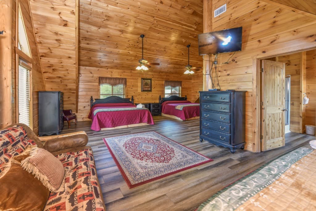 Spacious wood-paneled bedroom with two queen beds and dressers at Moose Hollow Lodge in Sevierville